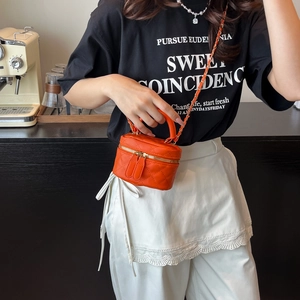 Mini borsa trapuntata arancione con cerniera dorata e tracolla a catena indossata da modella