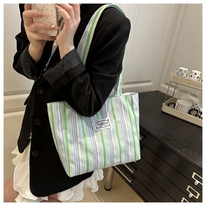 Detailed close-up of striped canvas tote bag with woven texture and fashion label