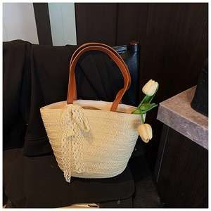 Detailed close-up of woven straw bag with lace bow and elegant leather handles