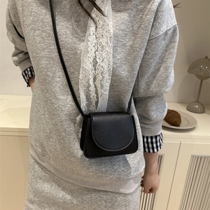 Minimalist black lychee texture mini crossbody bag with curved flap and thin shoulder strap