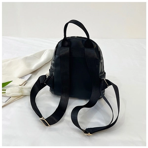 Detail view of the black mini backpack back with wide straps and gold metal adjusters