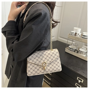 Détail du sac bandoulière avec motif géométrique beige et chaîne dorée sur mannequin