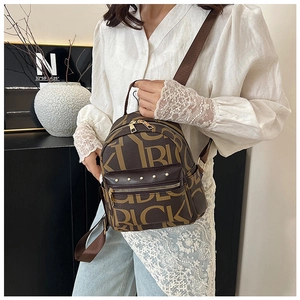 Detail of vintage brown backpack with yellow letters and golden metal rivets