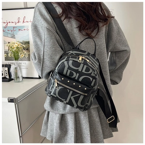 Detail of mini black letter print backpack with gold studs shown on a model