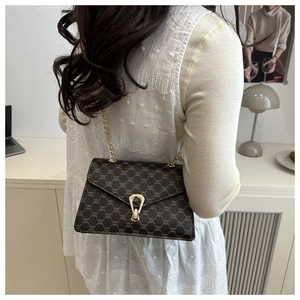Gros plan sur un sac bandoulière marron foncé à monogramme avec boucle dorée en coquille