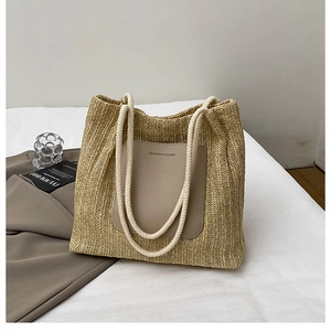 Detail of straw tote bag showing PU leather patch with text and woven texture
