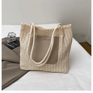 Detail of woven straw tote with brown leather pocket and natural cotton rope handles