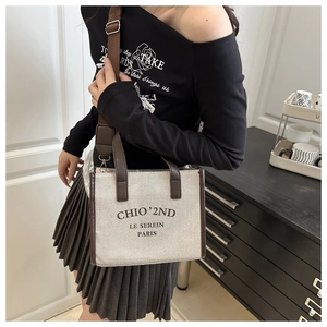 Détail du sac cabas en toile avec poignées en cuir marron et bandoulière tissée réglable