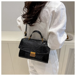 Detail of glossy black crocodile pattern shell bag with square gold-tone clasp