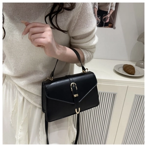 Sac à main élégant en cuir noir avec boucle dorée dans une scène lifestyle