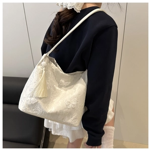 Détail du sac cabas en dentelle blanche avec broderie papillon et pendentif à pampilles