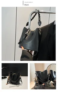 Detail of black glossy leather bucket bag featuring gold logo and woven handle textures