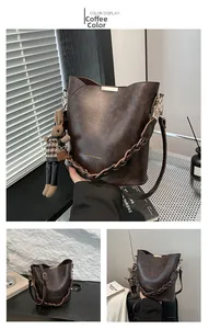 Detailed view of brown litchi pattern bucket bag with rabbit charm and woven strap