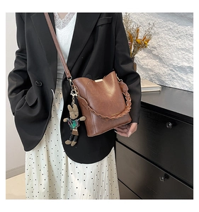 Close-up of a brown retro bucket bag with woven handle and a cute rabbit charm