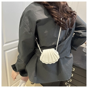 Detail view of a white shell-shaped mini crossbody bag with textured wavy ridges