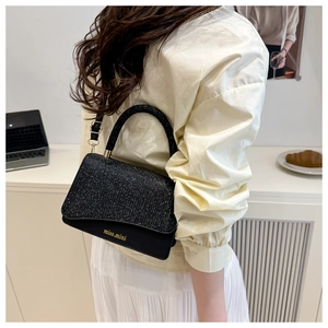 Detail of a chic black sequined crossbody bag worn over the shoulder in a cozy setting