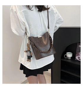 Detail of vintage brown bucket bag with woven handle and cute rabbit charm on a model