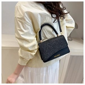 Detail view of the black crossbody bag with shimmering glitter flap and gold logo