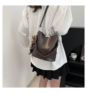 Detailed close-up of dark brown bucket bag with gold accents and a rabbit charm accessory