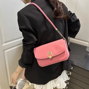 Pink PU leather shoulder bag with golden horseshoe buckle and chain strap on a black blazer