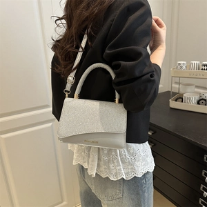 Silver sequin crossbody bag with gold hardware shown on model in modern room setting