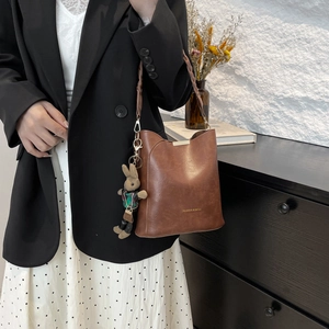 Vintage brown leather bucket bag with woven handle and cute rabbit charm for women
