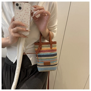 Detail of colorful striped woven handbag with leather handles and fashion logo patch