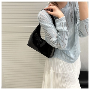 Close-up of black patent leather hobo bag with reflective finish on a female model
