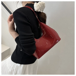 Macro view of glossy red patent leather underarm bag with golden hardware details
