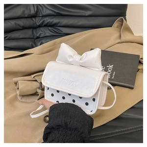 Close-up of mini crossbody bag with oversized white bow and black polka dot pattern