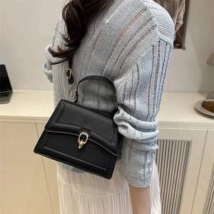 Minimalist black leather crossbody bag with golden ring lock and adjustable shoulder strap