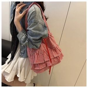 Detail view of the red gingham tote bag featuring triple ruffle lace trim on a model