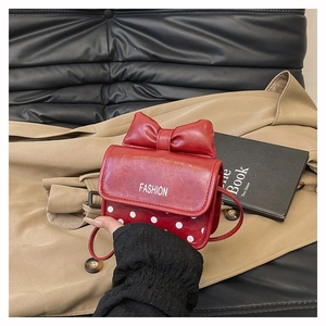 Detail of red mini crossbody bag with large bow and fashion print on black leather