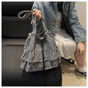 Close-up of gingham tote bag featuring double ruffle trim and black drawstring closure