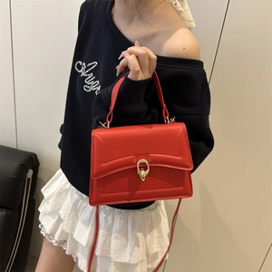 Minimalist red square crossbody bag with gold buckle and structured top handle design