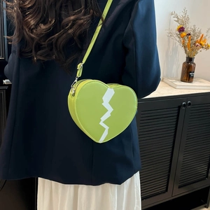 Lime green heart-shaped crossbody bag with white lightning detail on a fashion model