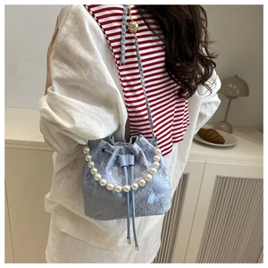 Detail of light blue lace bucket bag with pearl handle and butterfly accent on model