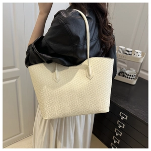 Chic cream woven tote bag with fine leather texture shown on shoulder for office commute style