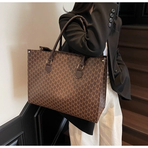 Détail de l'imprimé à lettres M et des doubles poignées du sac fourre-tout marron