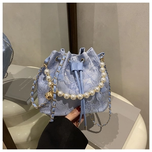 Detail of light blue jacquard bucket bag with pearl handle and golden ball charm