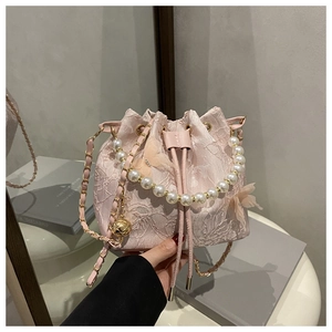 Detailed shot of pink lace bucket bag featuring pearl handle and chain strap with drawstring