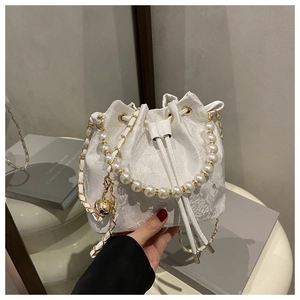 Detailed shot of white floral lace bucket bag with pearl handle and golden chain strap