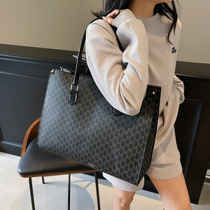 Grand sac cabas gris foncé avec motif M et longues anses porté par un mannequin féminin