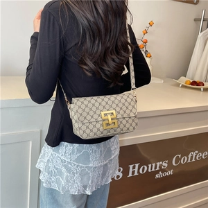 Retro monogram crossbody bag with gold buckle in minimalist coffee shop setting