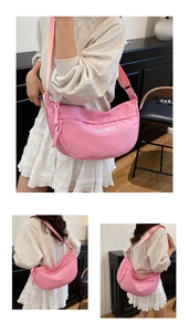 Detail of pink half-moon shoulder bag featuring white fashion text and adjustable strap