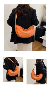 Detail of orange nylon half-moon crossbody bag with white FASHION print and wide strap