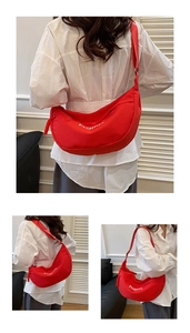 Detailed close-up of a red canvas crescent bag with white FASHION print and wide strap