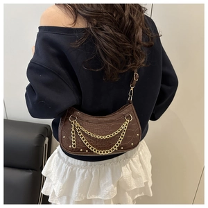Detail of brown faux leather shoulder bag featuring crocodile texture and gold chain