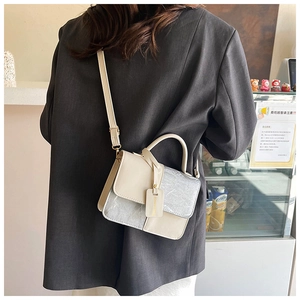 Detail view of contrast color mini square bag in beige and marble grey with strap