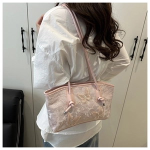Detail of pink lace shoulder bag featuring 3D butterfly embroidery and knotted strap